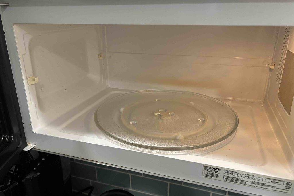 Clean microwave oven interior after reheating food using a damp paper towel cover.