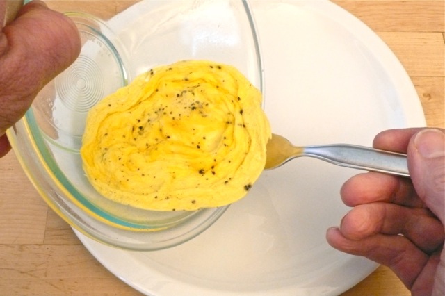 Sliding freshly cooked microwave cooked scrambled eggs onto a plate