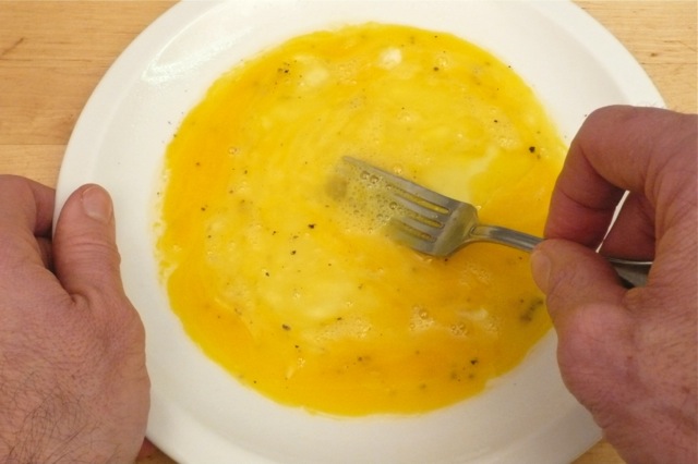 Breaking egg yolks and mixing eggs well before cooking eggs in the microwave oven