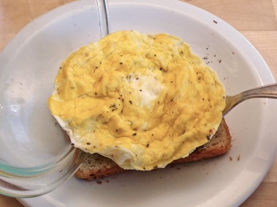 Microwave scrambled eggs on toast in white bowl.