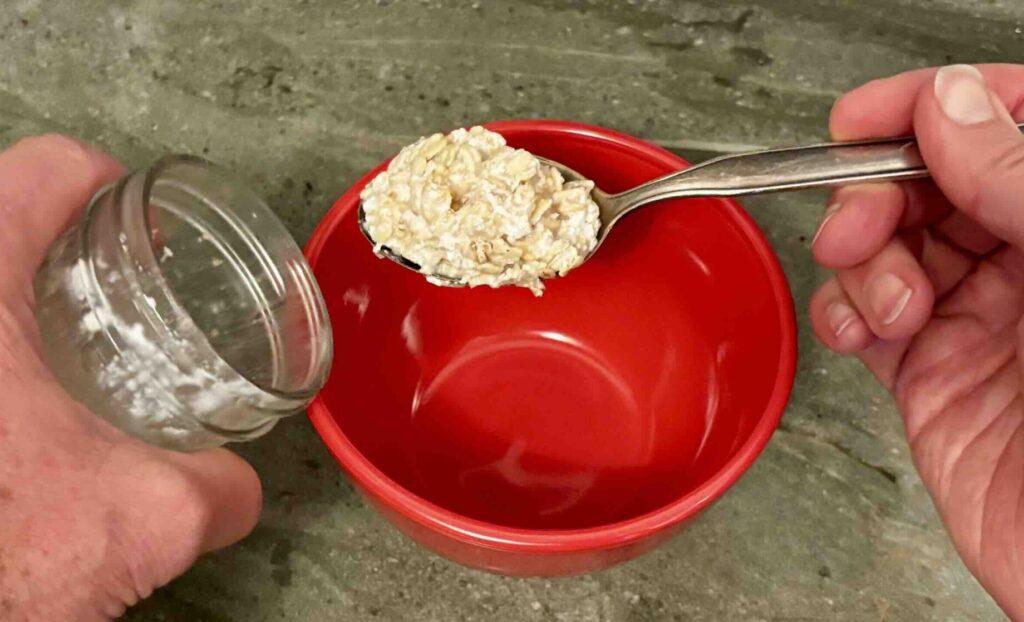 Adding well-soaked overnight oats to a bowl to make an easy savory oats meal