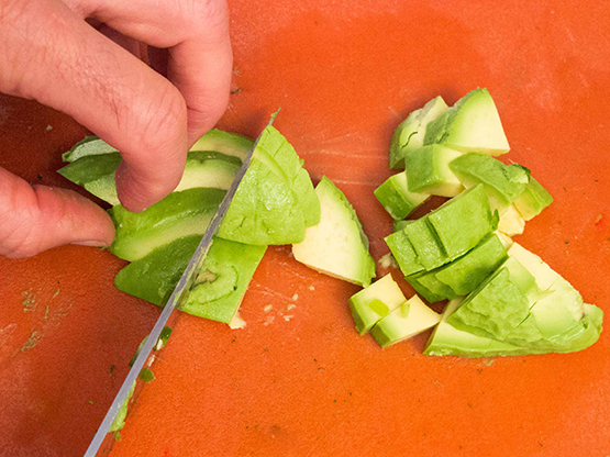 Fresh avocado being cut into quartered pieces.