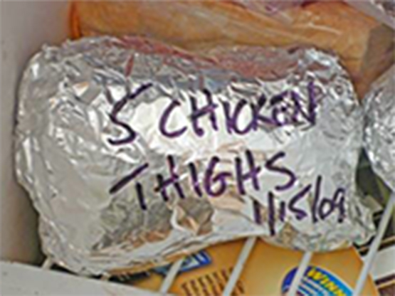 Food marked with a date and wrapped in plastic wrap and aluminum foil ready for freezing.